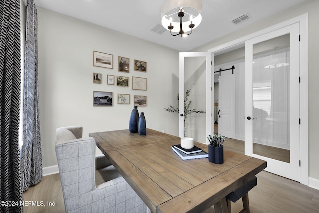 office space with a barn door, hardwood / wood-style flooring, and a notable chandelier