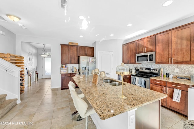 kitchen featuring appliances with stainless steel finishes, tasteful backsplash, a kitchen island with sink, a kitchen breakfast bar, and sink