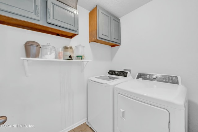 laundry area with cabinets, a textured ceiling, light tile patterned floors, and washing machine and dryer