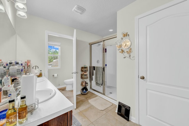 bathroom with a shower with shower door, toilet, vanity, and tile patterned flooring