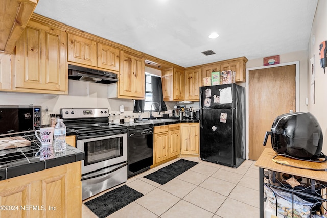 kitchen featuring tile counters, sink, light brown cabinetry, light tile patterned floors, and black appliances