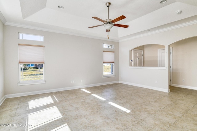 spare room with a tray ceiling, ceiling fan, and ornamental molding