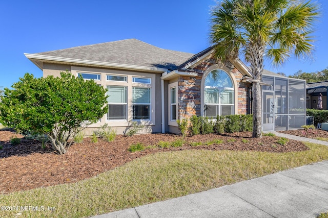 view of front of home featuring a front yard and glass enclosure