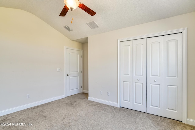 unfurnished bedroom with ceiling fan, a closet, light carpet, and vaulted ceiling