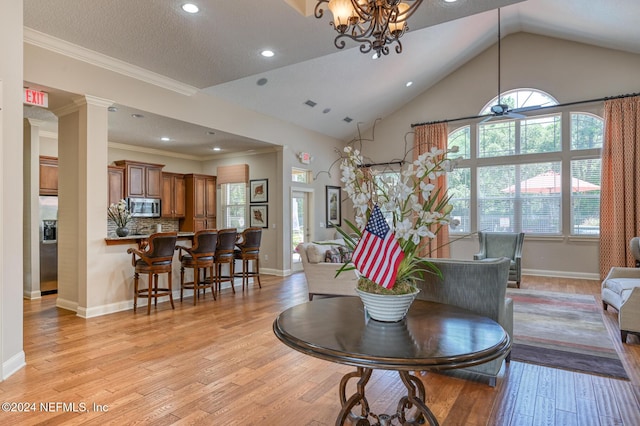 living room featuring ceiling fan with notable chandelier, light hardwood / wood-style floors, lofted ceiling, and crown molding