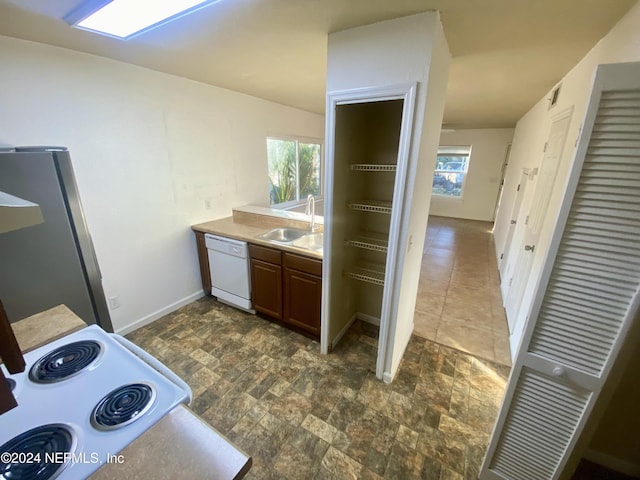 kitchen featuring white appliances, a wealth of natural light, and sink