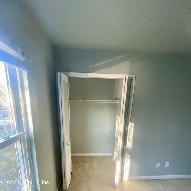 unfurnished bedroom with light colored carpet and a closet