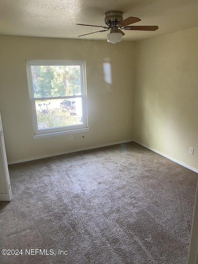 empty room with carpet flooring, ceiling fan, and a textured ceiling