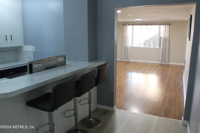 kitchen with a kitchen bar, light hardwood / wood-style flooring, and white cabinets