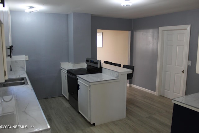 kitchen featuring sink, electric range, light hardwood / wood-style floors, white cabinets, and kitchen peninsula