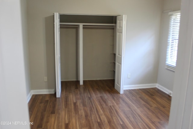 unfurnished bedroom with dark hardwood / wood-style flooring and a closet