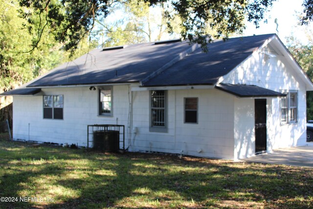 back of property featuring cooling unit and a lawn