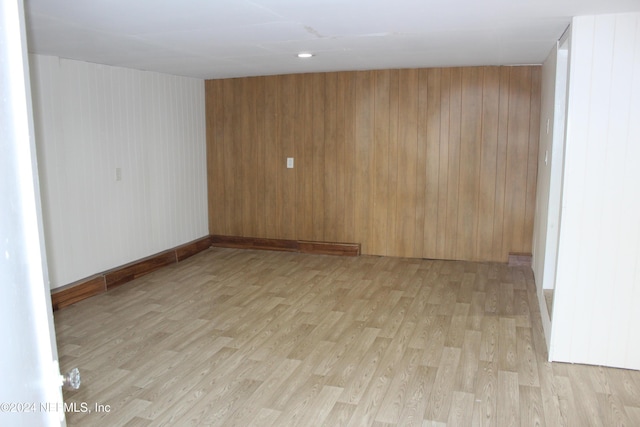 unfurnished room featuring wooden walls and light hardwood / wood-style floors