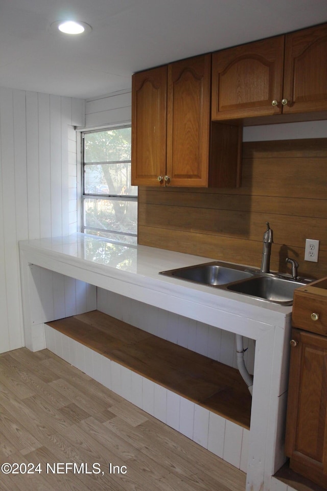 kitchen featuring sink, wooden walls, and light wood-type flooring