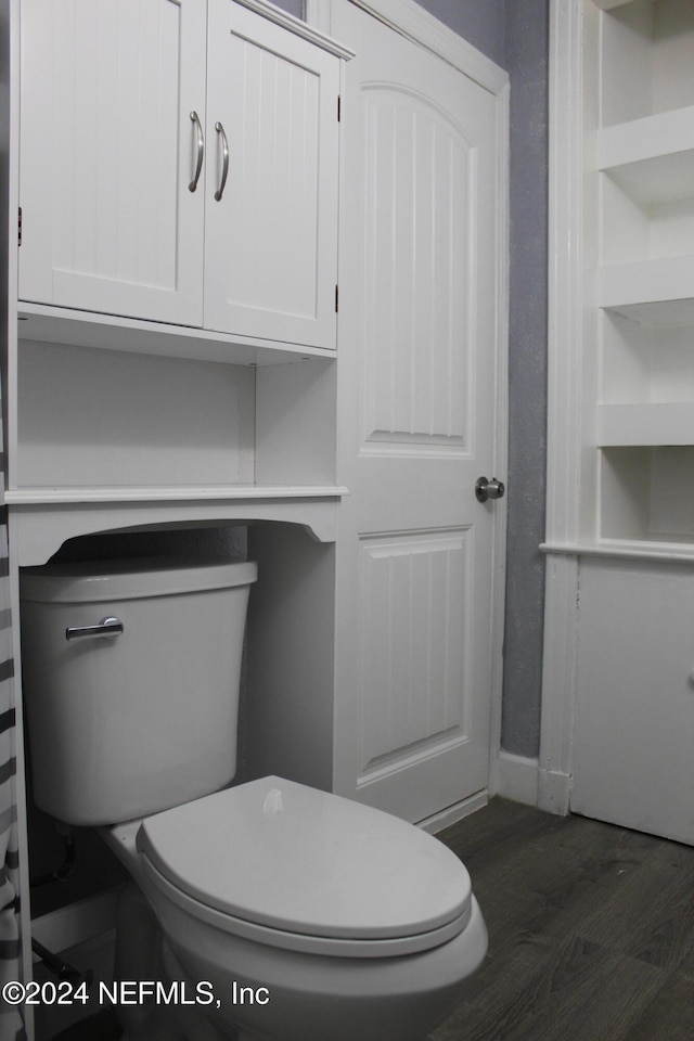 bathroom with hardwood / wood-style flooring, built in features, and toilet