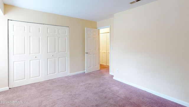 unfurnished bedroom featuring light carpet and a closet