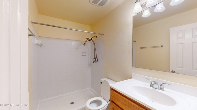 bathroom with tiled shower, vanity, and toilet