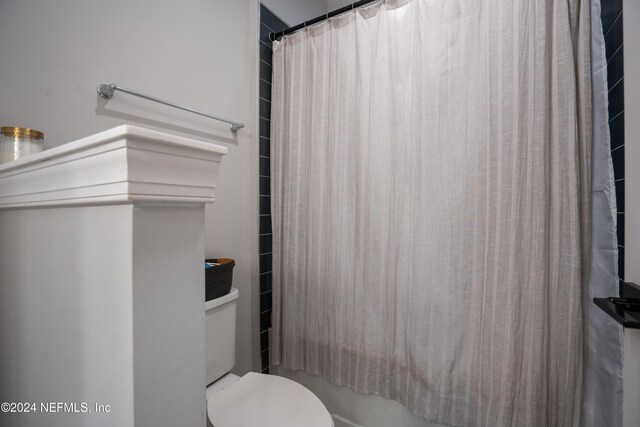 bathroom with shower / bath combo with shower curtain and toilet