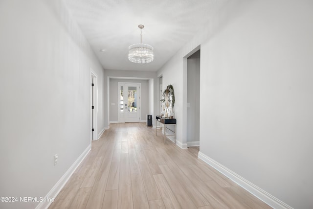 corridor with a notable chandelier and light wood-type flooring