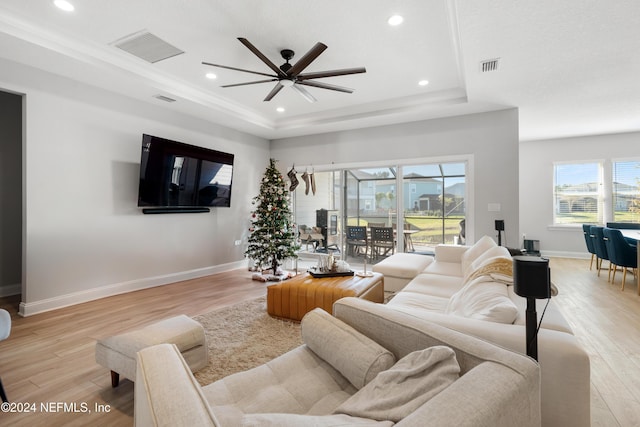 living room with ceiling fan, light hardwood / wood-style floors, and a raised ceiling