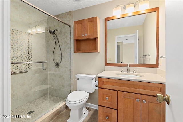 bathroom with a shower with door, vanity, a textured ceiling, and toilet