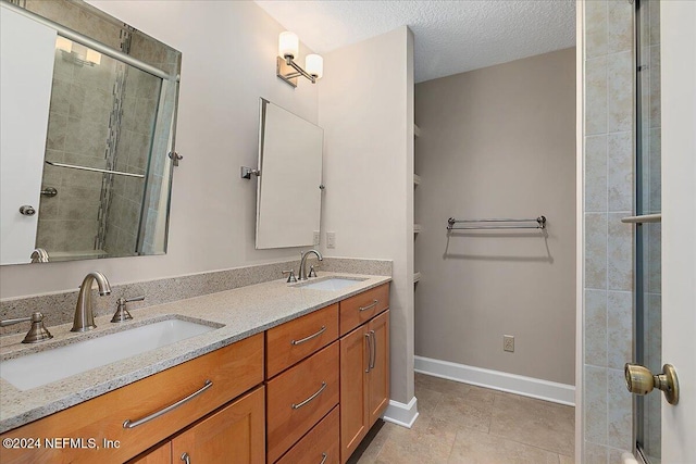 bathroom featuring vanity, tile patterned flooring, a shower with door, and a textured ceiling