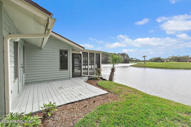 exterior space with a water view, a sunroom, and a lawn