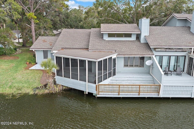 rear view of house featuring a deck with water view, a yard, and a sunroom