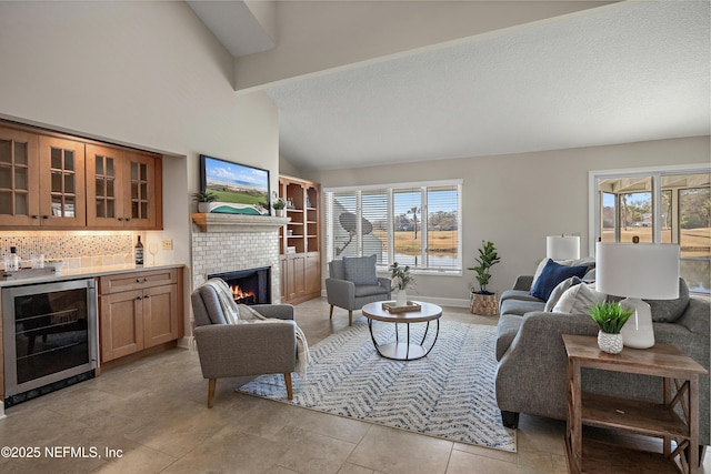 tiled living room with bar, high vaulted ceiling, wine cooler, a textured ceiling, and a brick fireplace