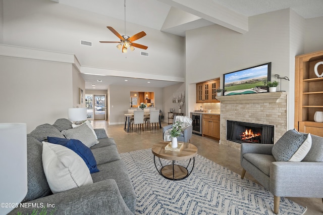 living room with wine cooler, bar area, beamed ceiling, ceiling fan, and a high ceiling