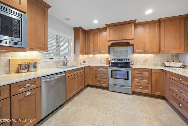 kitchen featuring sink, backsplash, premium range hood, and appliances with stainless steel finishes