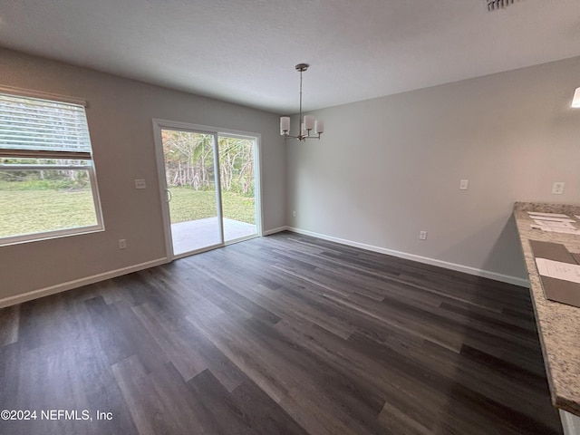 unfurnished dining area featuring a chandelier and dark wood-type flooring