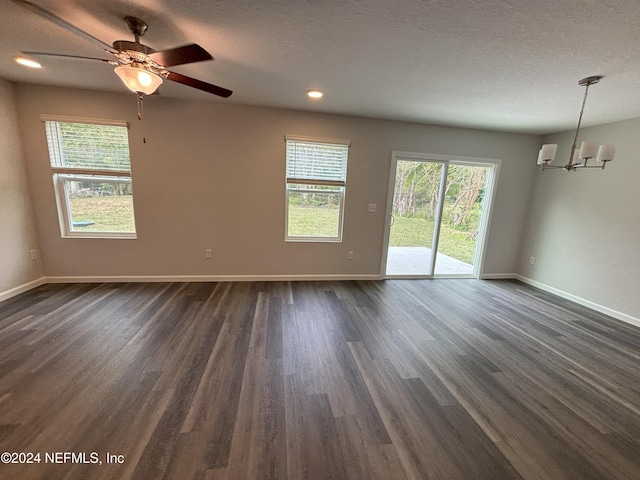 spare room with ceiling fan with notable chandelier, dark hardwood / wood-style flooring, and a textured ceiling