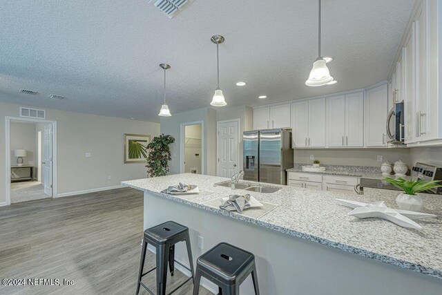 kitchen with sink, white cabinets, stainless steel appliances, and decorative light fixtures