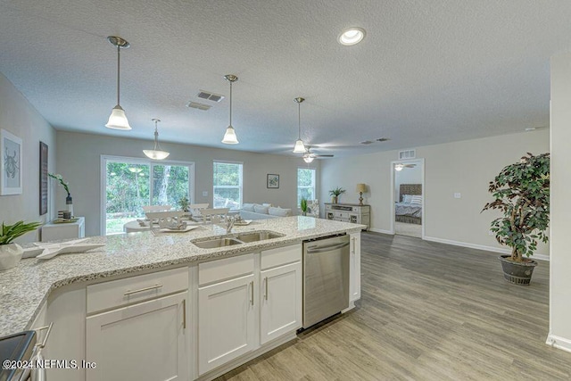 kitchen featuring stainless steel dishwasher, sink, decorative light fixtures, light hardwood / wood-style floors, and white cabinetry