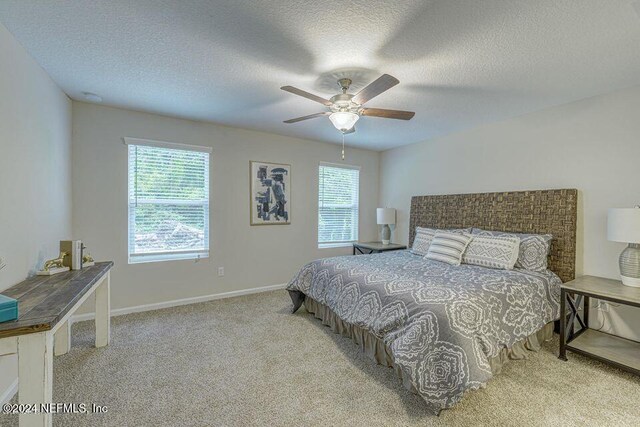 bedroom featuring multiple windows, ceiling fan, light carpet, and a textured ceiling