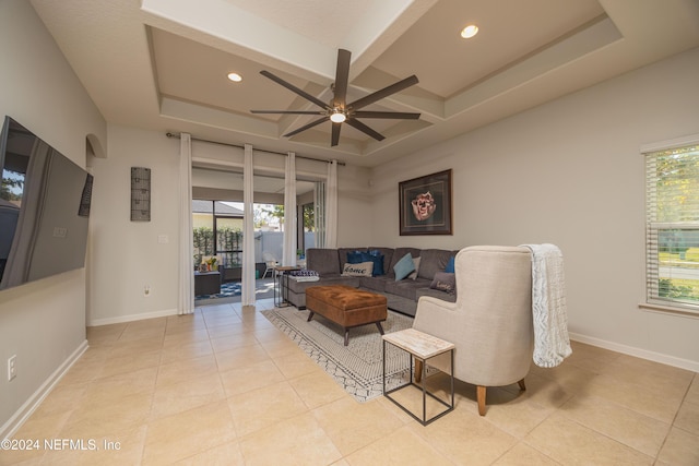 tiled living room with beam ceiling, a raised ceiling, and ceiling fan