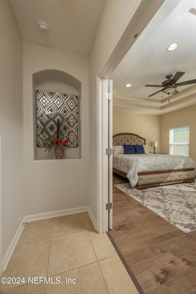 bedroom with ceiling fan, a textured ceiling, and hardwood / wood-style flooring