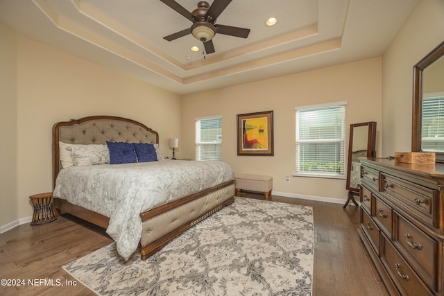 bedroom featuring a raised ceiling, ceiling fan, and dark wood-type flooring