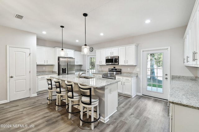 kitchen with appliances with stainless steel finishes, white cabinetry, and a healthy amount of sunlight