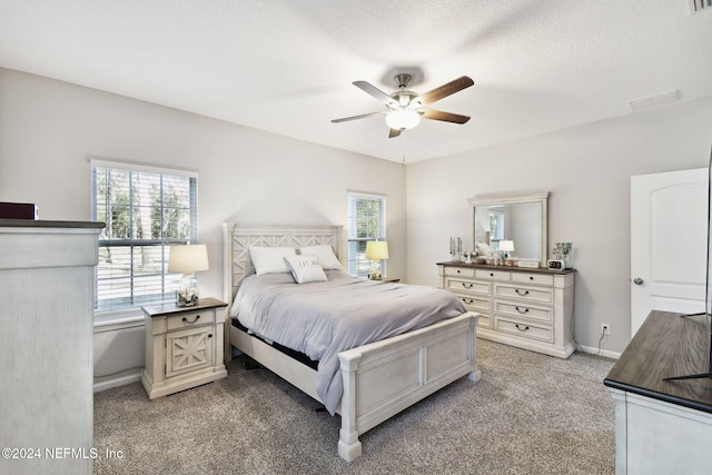 carpeted bedroom with a textured ceiling, multiple windows, and ceiling fan