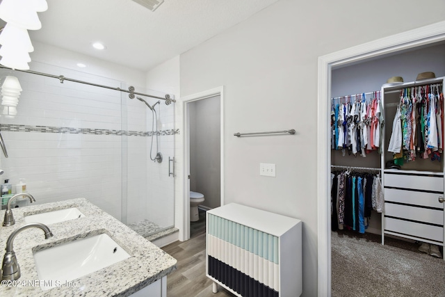 bathroom with radiator, vanity, a shower with door, hardwood / wood-style floors, and toilet