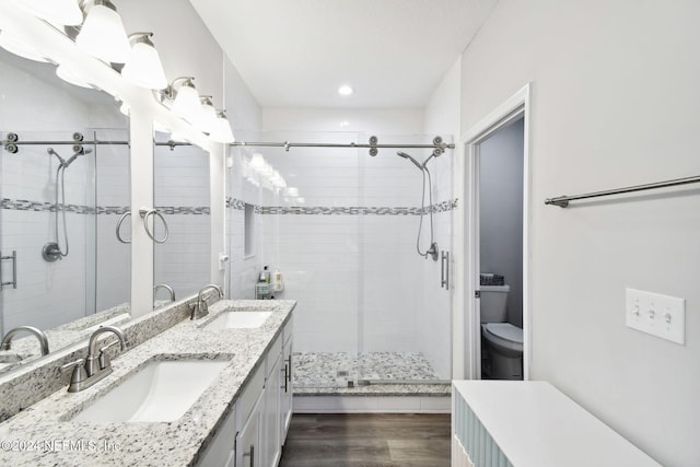 bathroom with hardwood / wood-style floors, vanity, an enclosed shower, and toilet