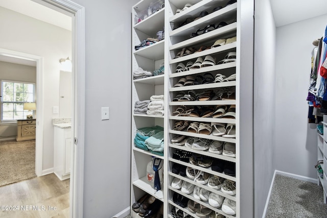 walk in closet with light hardwood / wood-style flooring