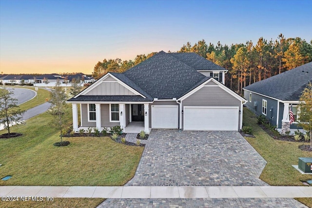 view of front of house featuring a yard, covered porch, and a garage