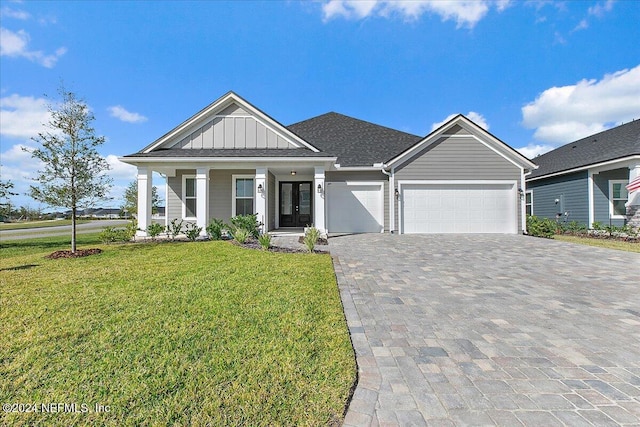 view of front of home with a porch, a garage, and a front lawn