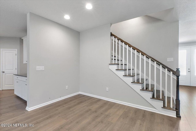 stairs featuring hardwood / wood-style floors and a textured ceiling