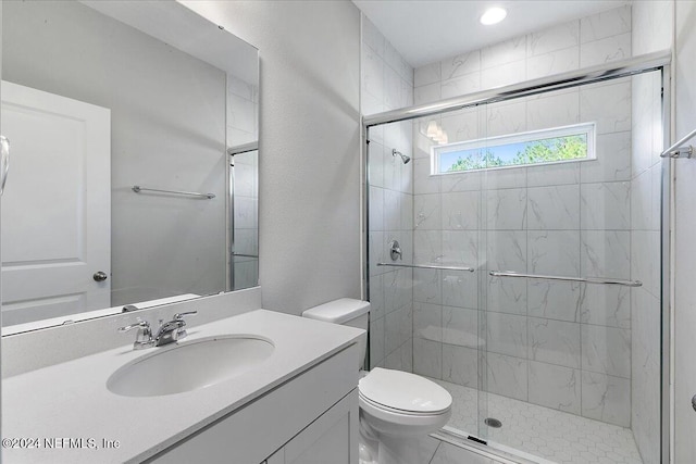 bathroom with a shower with door, vanity, and toilet