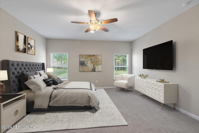 carpeted bedroom with ceiling fan and a textured ceiling