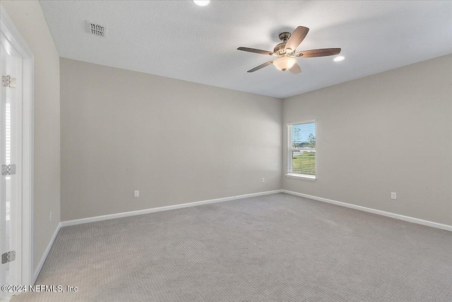 unfurnished room featuring light carpet, ceiling fan, and a textured ceiling